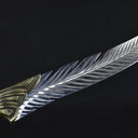 A close-up highlighting the curved edge and layered feather pattern engraving on the silver blade of a fixed knife.