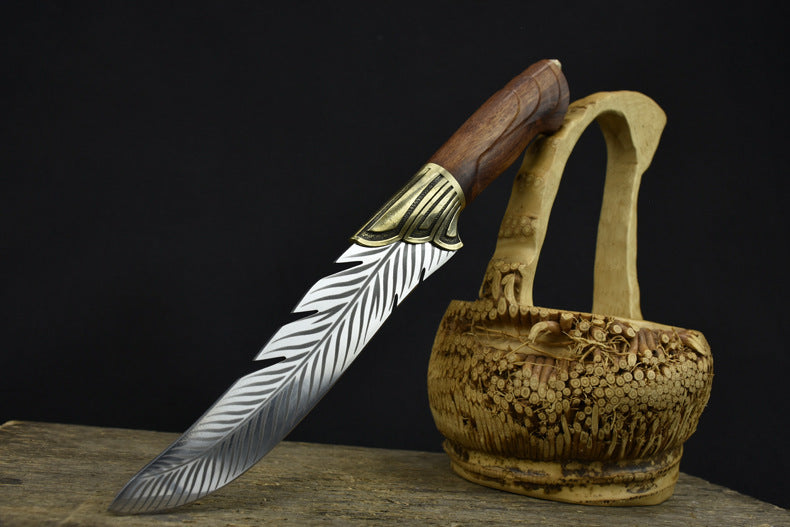 An engraved feather blade knife with a brass bolster and wooden handle, displayed next to a finely carved hollow wooden basket.
