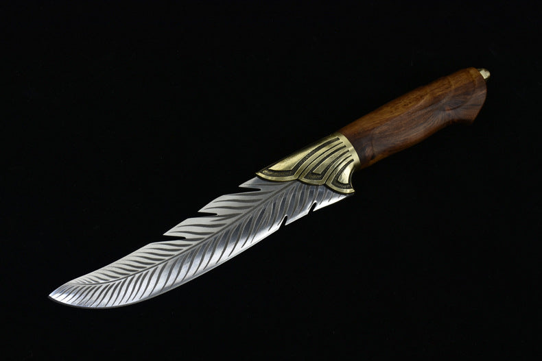 An open fixed blade knife featuring an engraved feather-patterned silver blade and a wooden handle, displayed horizontally on a black background.