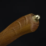 A close-up of the wooden handle's butt end, featuring a brass nut and ball end cap, displayed against a dark background.