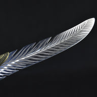 A macro shot showing the unique feather-like serrations and detailed engraving along the edge of the silver blade.