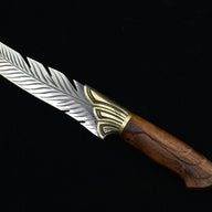 A close-up of the wooden handle and textured brass bolster of a feather-blade fixed knife, displayed on a black background.