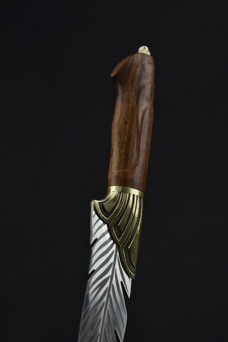 A close-up of the polished wooden handle and brass bolster of a custom feather blade knife.