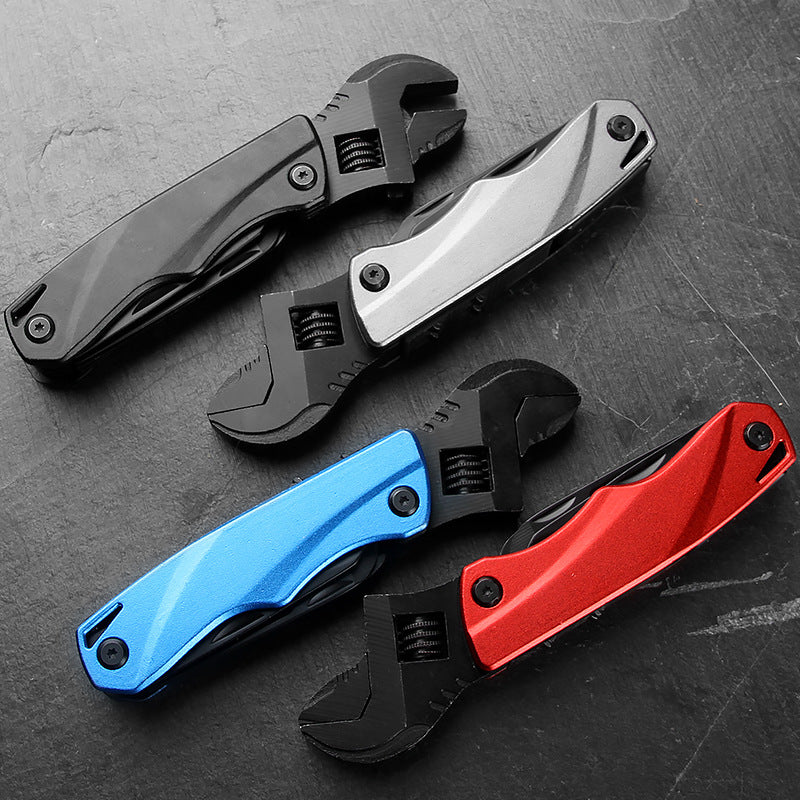 Four folding adjustable wrench multi-tools in black, silver, blue, and red colors, arranged on a dark textured surface.