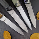 A macro shot of four folding knife blades showing the fine grind lines, sharp tips, and metallic finish.