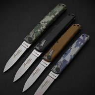 Four open lever-action folding knives displayed in a row on a dark surface, featuring green camo, black, tan, and blue digital camo handles.