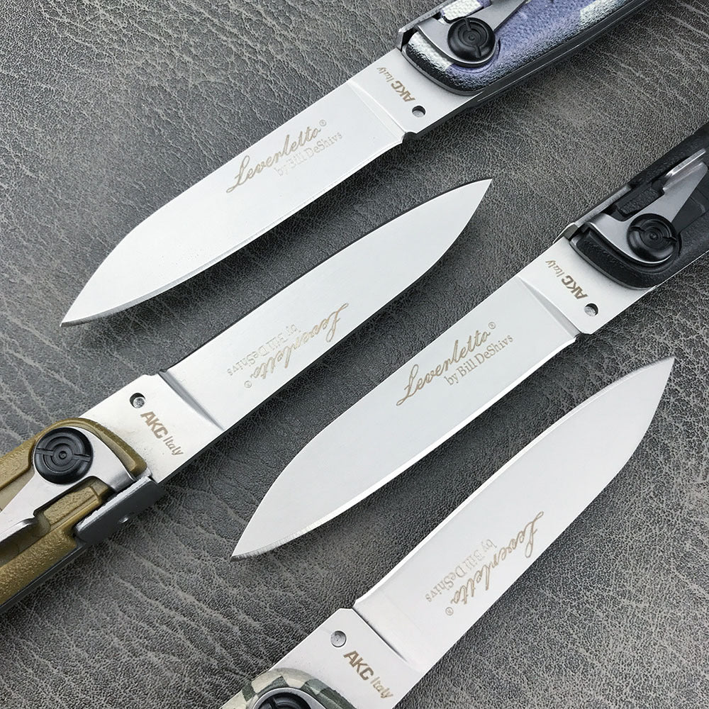 A close-up view of four folding knife blades showing the engraved brand logo and model text on the bright steel surface.