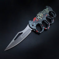 An open knuckle duster folding knife with a grey textured skull graphic handle and a silver blade featuring a cutout and the BROWNING logo, displayed on a dark background.