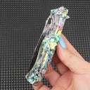 Close-up of a hand-held folded knife featuring a stunning abalone shell handle, displaying natural pearl-like iridescence and colorful textures, highly valuable for collection and decoration.