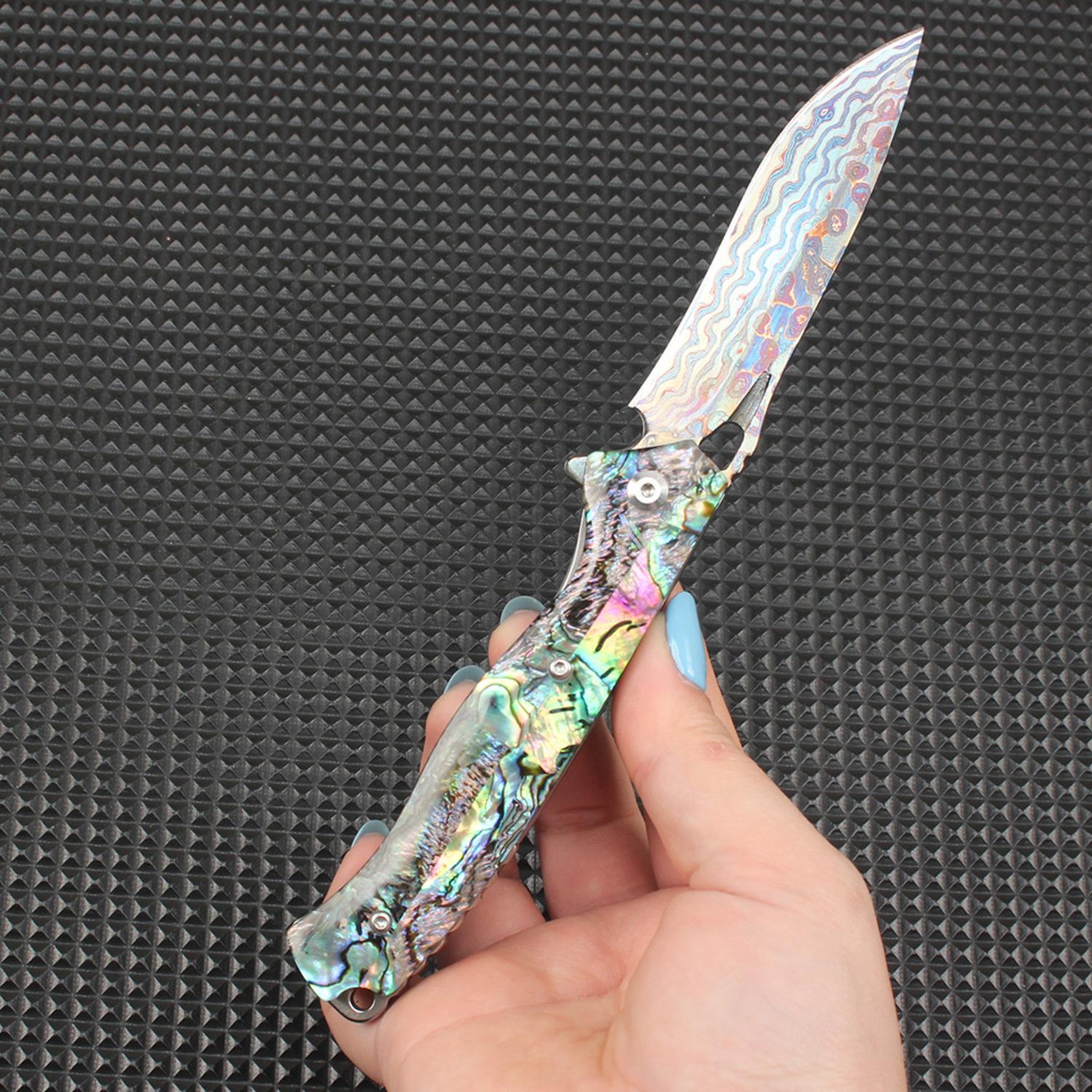 Display of this abalone handle folding knife fully opened in hand, with the colorful Damascus steel blade perfectly complementing the iridescent shell handle, offering both practical cutting capability and artistic aesthetics.