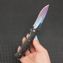 Close-up of the fully opened folding knife, featuring a stunning colorful Damascus blade paired with a dark textured handle, showcasing premium EDC knife aesthetics.