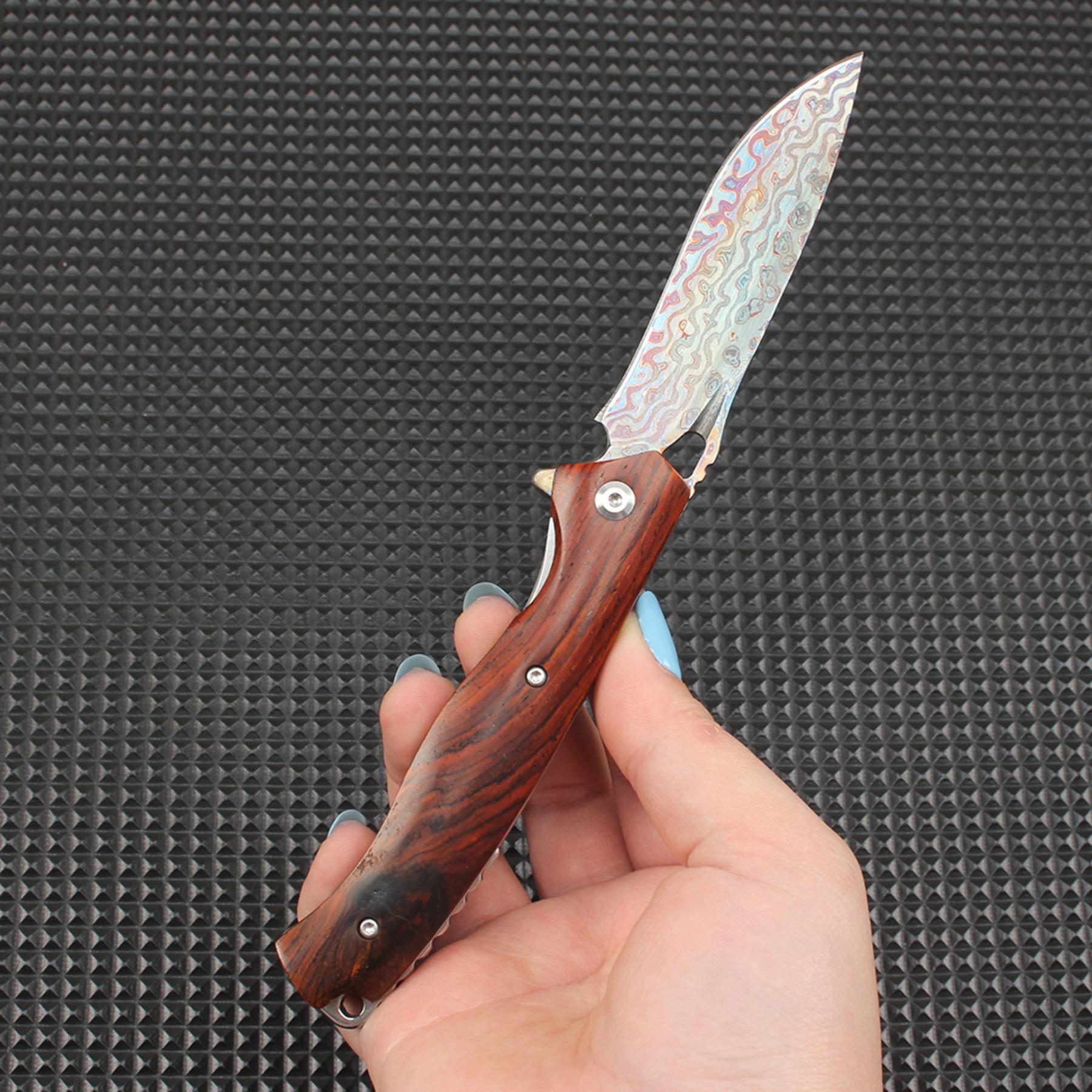 Close-up of this redwood handle folding knife in the open position, showing the visual contrast between the colorful Damascus blade and the classic redwood handle, showcasing the premium EDC knife craftsmanship.