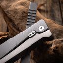 Close-up of the back of an industrial-style all-metal folding knife handle, clearly showing the dual-screw reinforcement, pivot details, and brushed metal texture, highlighting its sturdy mechanical design.