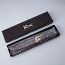 An unboxing shot of a JCHNC brand M390 folding knife wrapped in bubble wrap, resting inside its black packaging box on a white surface.