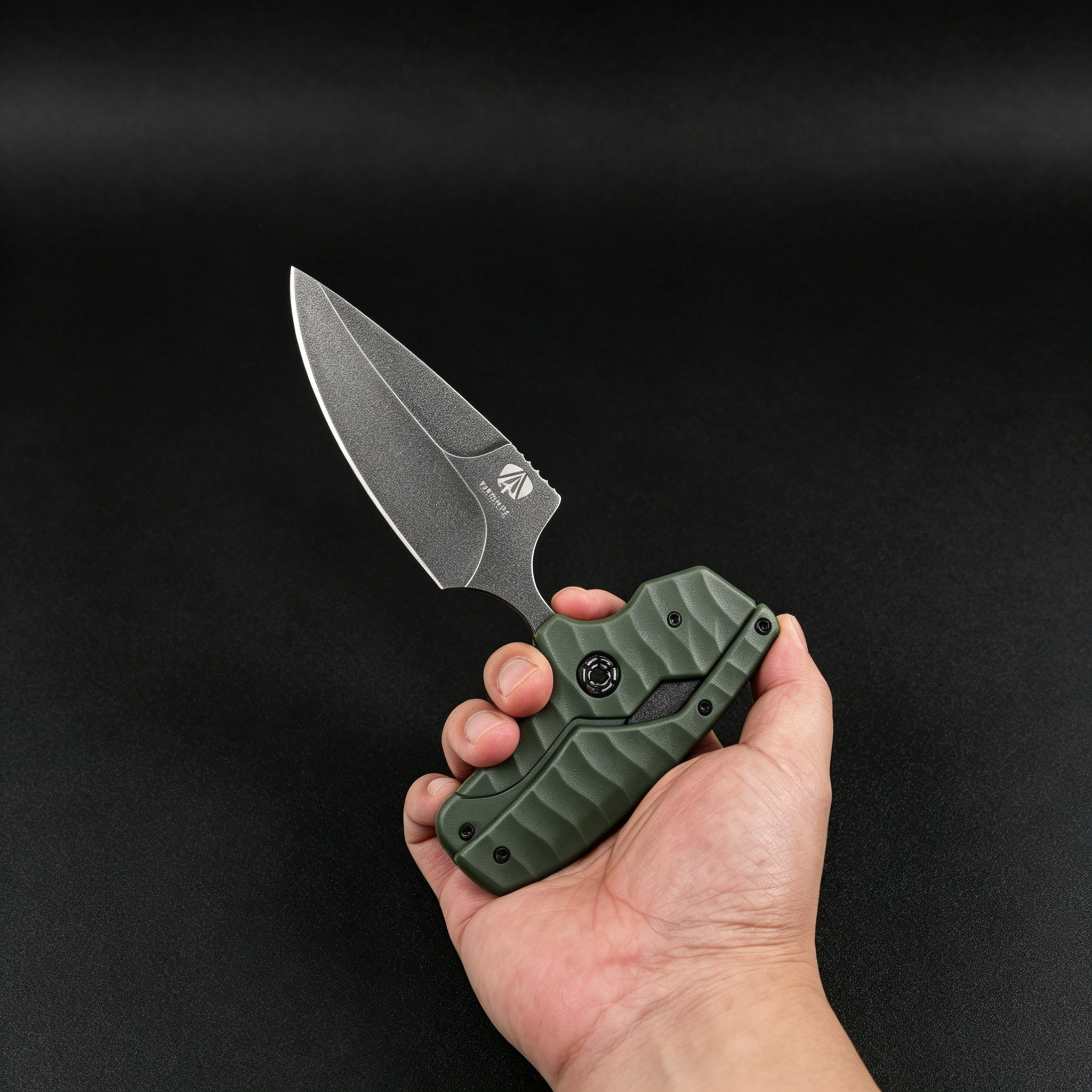 A hand holding an open Kizer folding knife with an olive green textured handle and a silver stonewashed blade, displayed against a dark background.