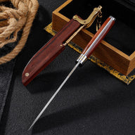 A folding knife with an M390 blade inserted into its wooden sheath, featuring a brass mechanical lock and key ring, displayed on a dark background with rope and a wooden box.