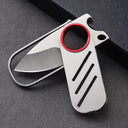 A close-up of a partially open EDC folding knife, showcasing its silver steel blade, red ring, and compact slide mechanism on a dark fabric background.