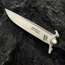 A close-up of the silver blade of a Noks folding knife, clearly showing the Cyrillic engraving and brand logo.