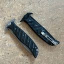 Two closed Noks folding knives with black handles and silver pocket clips, displayed on a light wooden background.