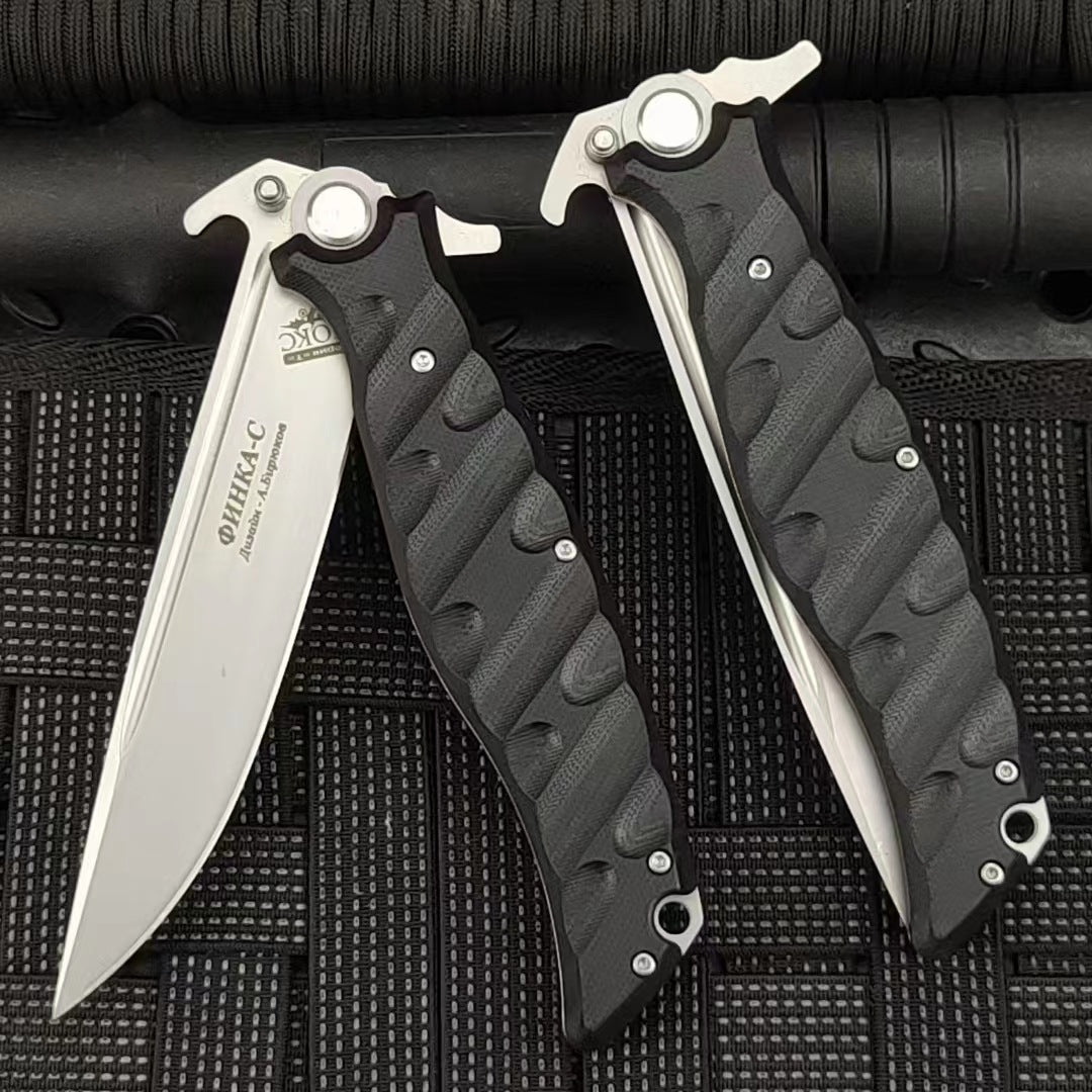 An open and a closed Noks folding knife displayed on a black rope-textured surface, showing the Cyrillic engraving on the blade.