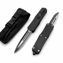 Two black OTF knives with carbon fiber handles and silver blades, displayed next to a black nylon sheath.
