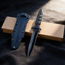 Black tactical double-edged fixed blade knife with an all-black finish, featuring a non-slip cross guard and tactical Kydex sheath, displayed on an outdoor tactical backpack to showcase its rugged outdoor style.