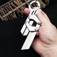 A hand holding a silver folding knife with a ring handle and mechanical linkage design, displayed on a dark background with textured details.
