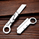 Two silver folding knives with ring handles and mechanical linkage designs, one open and one closed, displayed on a dark wooden background.