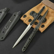 Two open slim tactical folding knives, one with a silver blade and one with a black blade, displayed next to tan tactical gloves and black sheaths on a dark background.