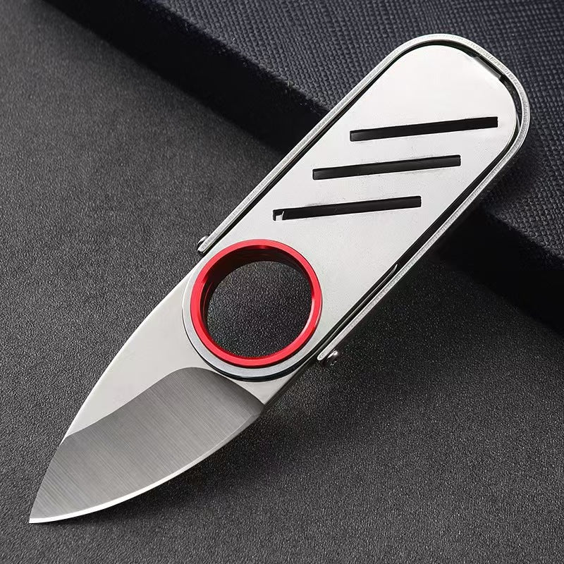 An open slim EDC folding knife with a brushed silver steel body, red finger ring, and three horizontal slots, displayed on a dark background.