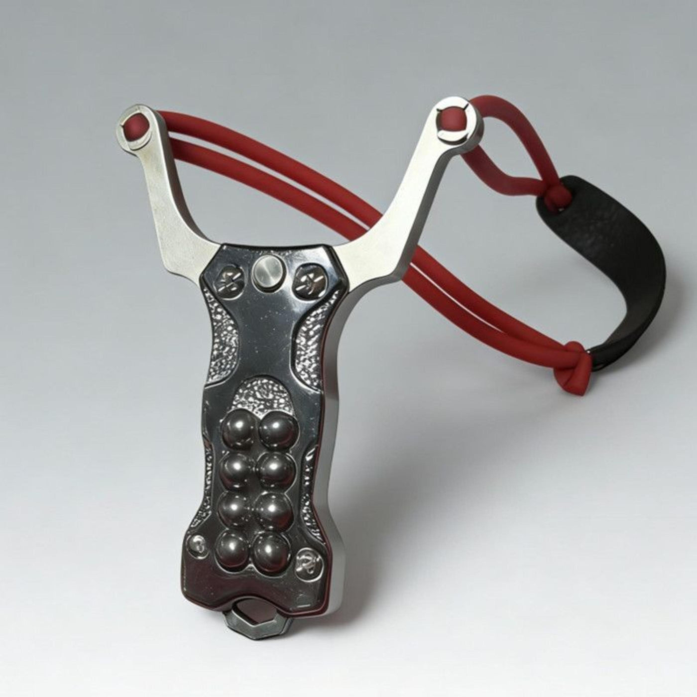 A silver stainless steel EDC slingshot with a red band and steel ball storage, displayed on a white background.