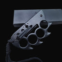 A closed black Tac-Force folding knife with a knuckle duster handle, black pocket clip, and lanyard, displayed on a dark background.