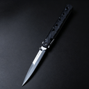 An open Tac-Raven folding knife with a silver blade and a black handle featuring rectangular cutouts and angled grooves, displayed on a dark background.