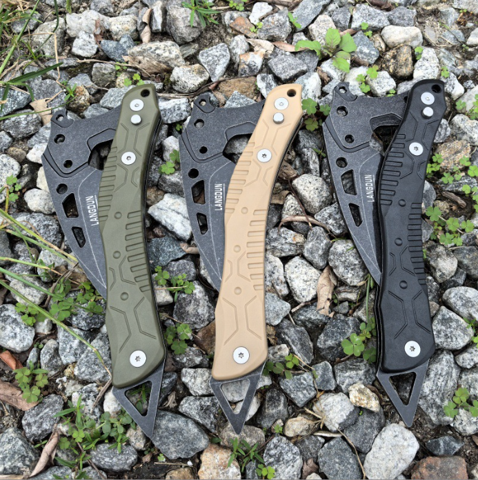 Three tactical breaching tools displayed side by side in sand, olive green, and black finishes, set against a rugged gravel and wild grass background.
