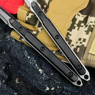 A close-up of two slim tactical folding knife handles, showing the detailed groove textures on the black and silver/grey handles, displayed on a dark rocky surface.