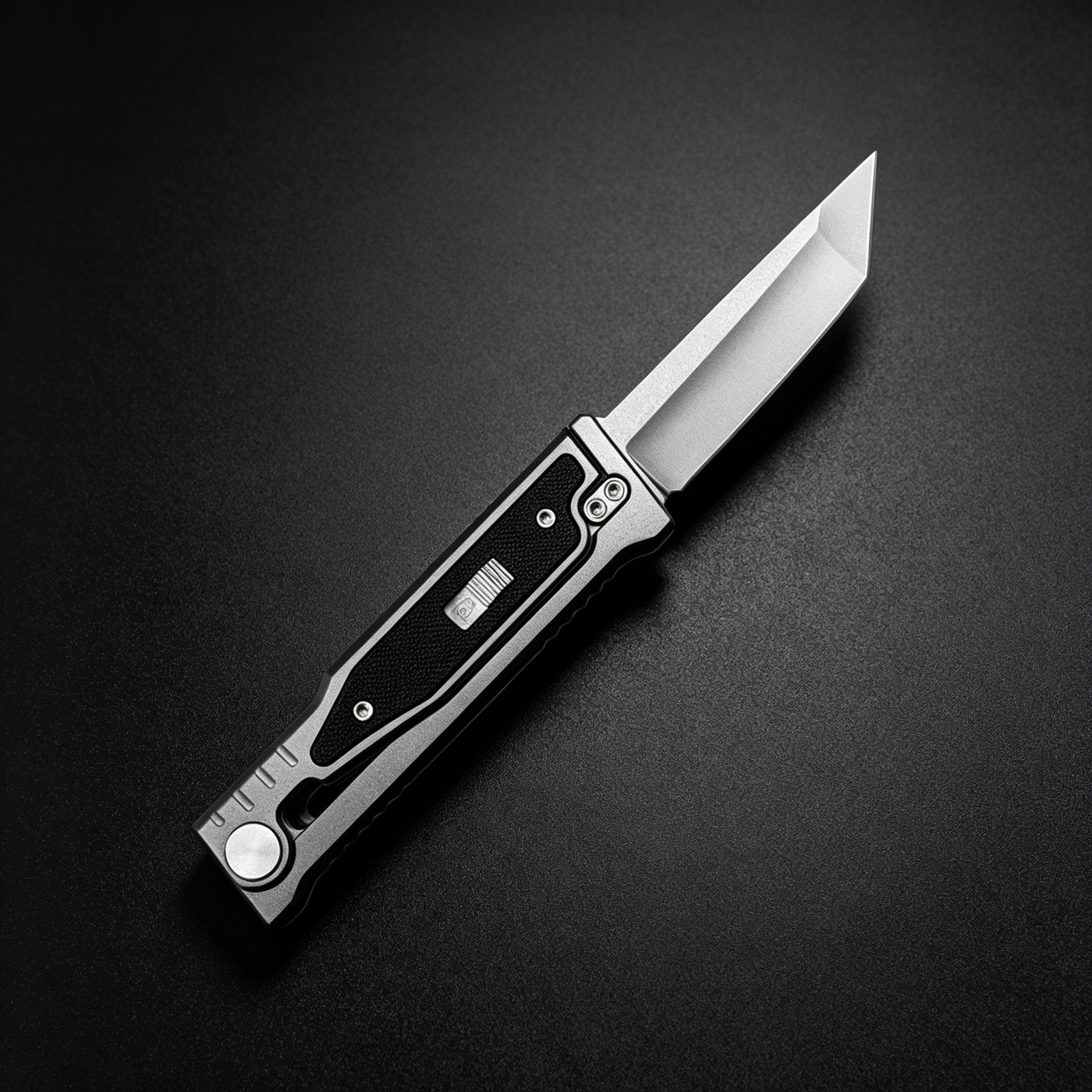 An open tactical folding knife with a grey handle and black insert, displayed on a dark background.