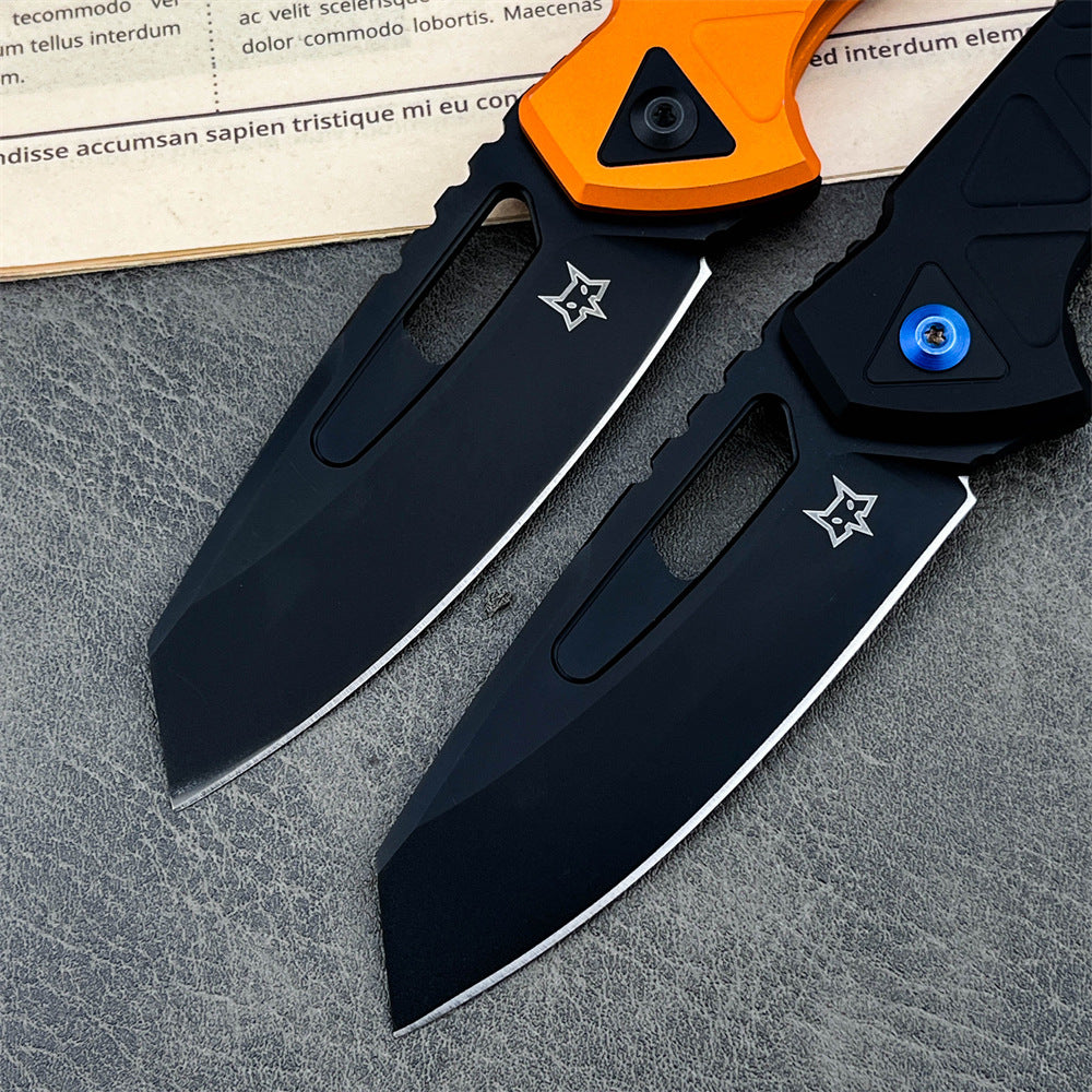 A close-up of two open tactical folding knives with black blades. The knife on the left has an orange handle, and the knife on the right has a black handle with a blue pivot screw, displayed on a textured grey surface.