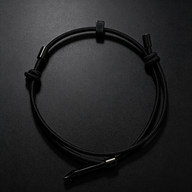 A black tactical handcuff key worn as a bracelet, featuring an adjustable cord, sliding bead, and a metal key insert, displayed on a dark background.