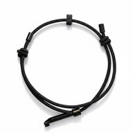 A clear product shot of a black wearable tactical handcuff key with an adjustable loop, knot details, and a metal key insert, on a white background.