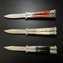 Three open balisong butterfly knives with silver blades and different handle materials: wood, pearl, and black, displayed horizontally on a dark background.