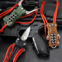 Three EDC slingshots in black, green, and tan G10 handles, displayed together on a black tactical rifle, with the black model featuring the knife blade deployed.