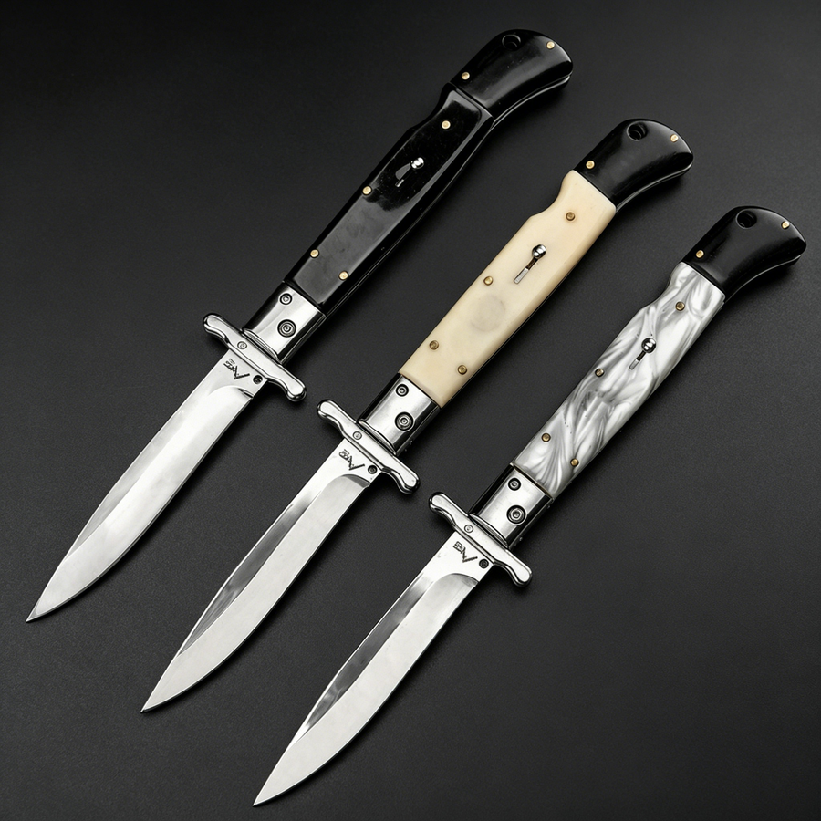 Three open Italian stiletto folding knives with silver blades and crossguards, featuring black, creamy white, and black-and-white marbled handles, arranged diagonally on a dark background.