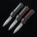 Three open out-the-front tactical knives with silver blades and black, bronze, and red handle accents, displayed on a dark background.