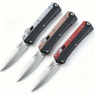 Three open out-the-front folding knives with black, bronze, and red handles and silver blades, displayed on a white background.