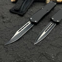 Two black OTF knives with silver blades and different blade shapes, displayed with a black nylon sheath on a rough textured surface with wood.