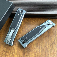 Two closed tactical folding knives shown from the back side, highlighting the pocket clips, on a wooden surface.