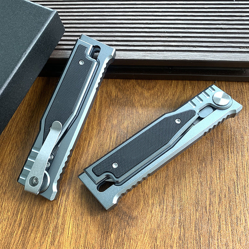 Two closed tactical folding knives shown from the back side, highlighting the pocket clips, on a wooden surface.