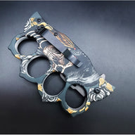 The back side of a closed knuckle duster folding knife, showing the black pocket clip and the continuation of the wolf and skull graphic on the handle.