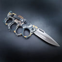 The back side of an open knuckle duster folding knife, highlighting the black pocket clip, textured handle, and the blade logo, on a dark background.
