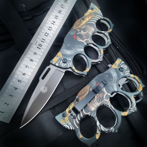 An open and a closed custom graphic knuckle duster knife displayed with a ruler on a tactical bag, showing the overall length and size for reference.
